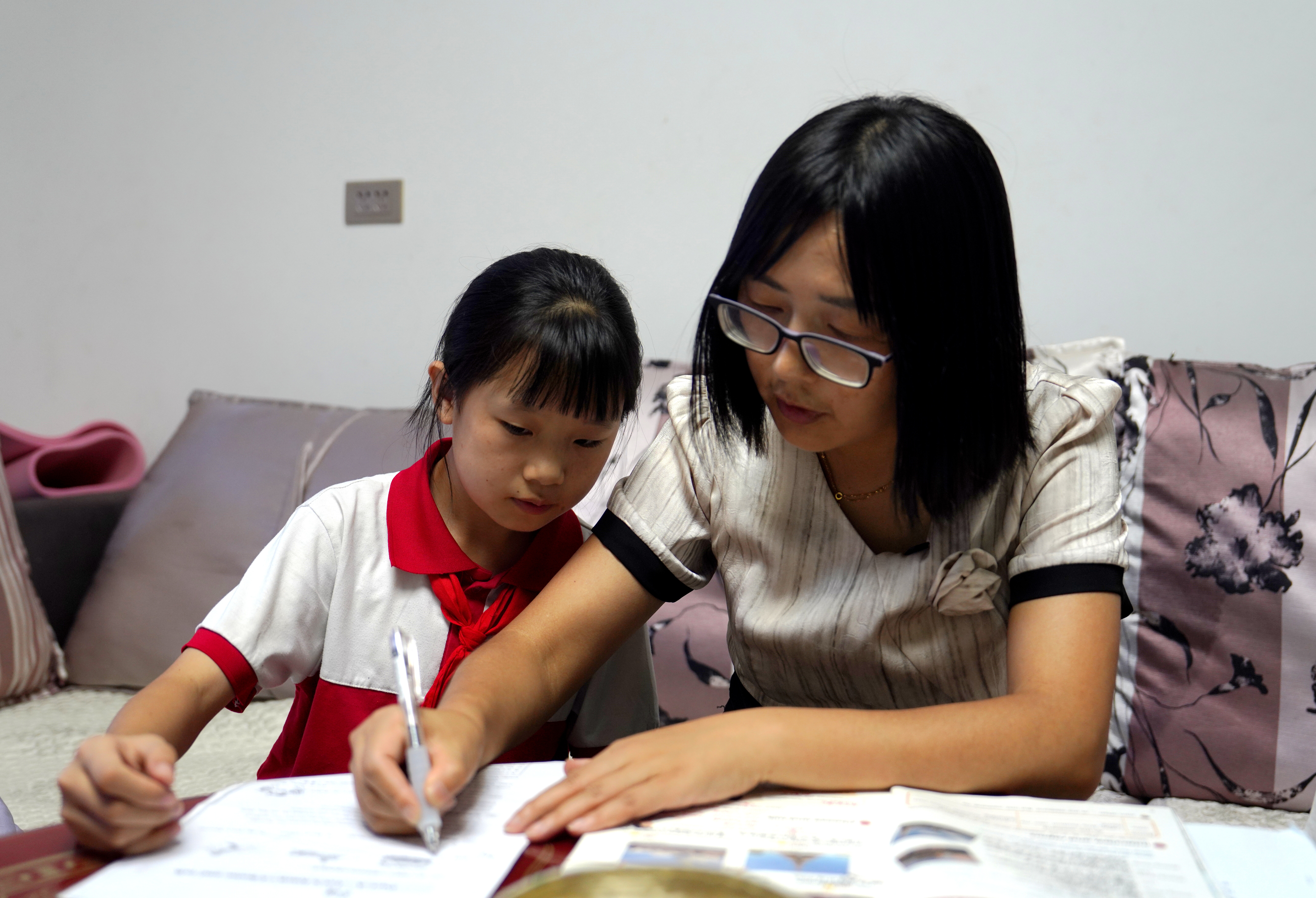 9月2日,马文丽在家访时辅导学生写作业。王金娥 摄