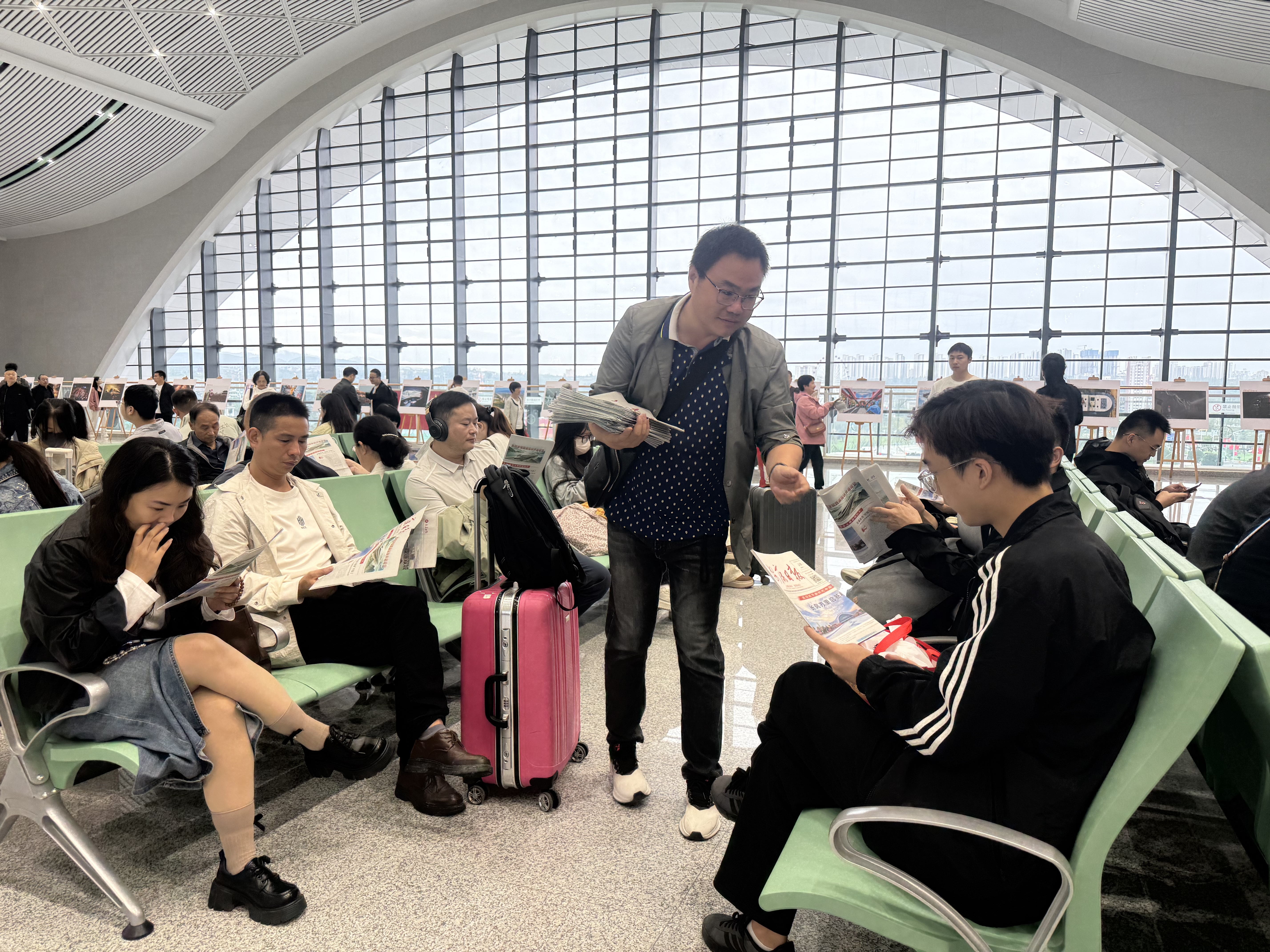 9月28日,安康市融媒体中心工作人员在安康西站候车大厅为旅客赠阅高铁专刊。 雷文静 摄